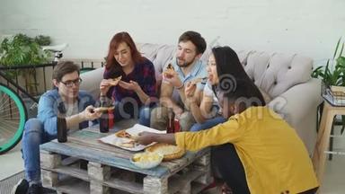 一群年轻的朋友在家里开派对，吃披萨从桌子上<strong>拿下</strong>来。学生聊天，玩得开心